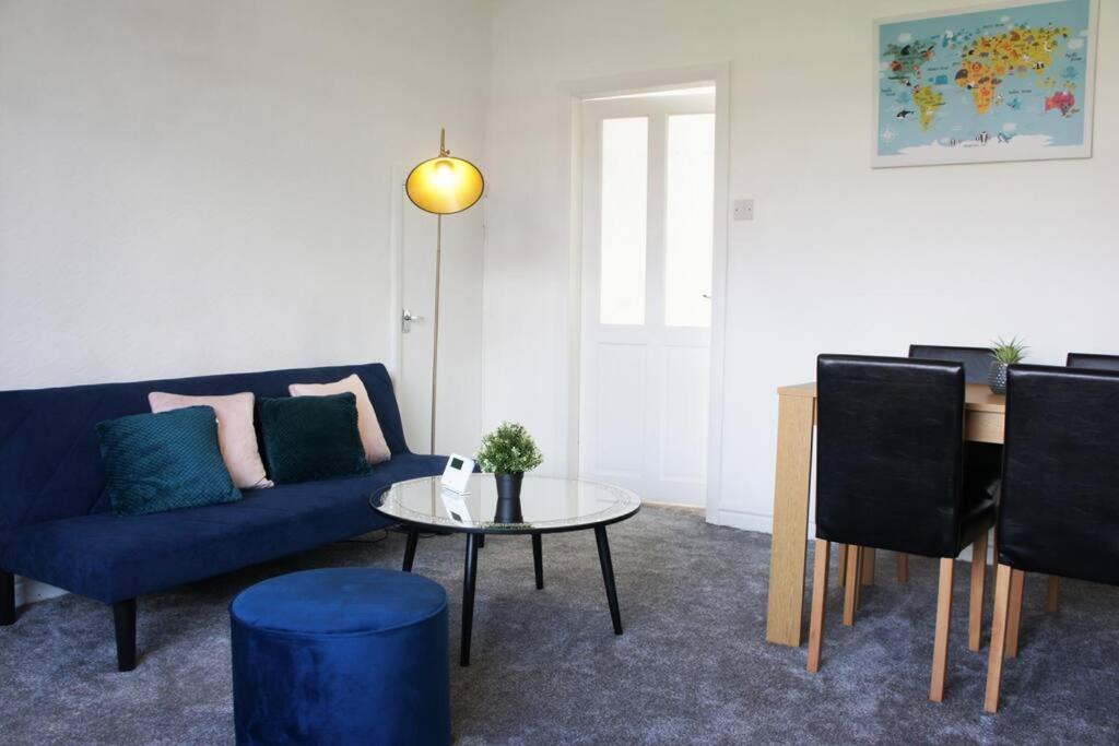 ein Wohnzimmer mit einem blauen Sofa und einem Tisch in der Unterkunft Middleton, Manchester in Middleton