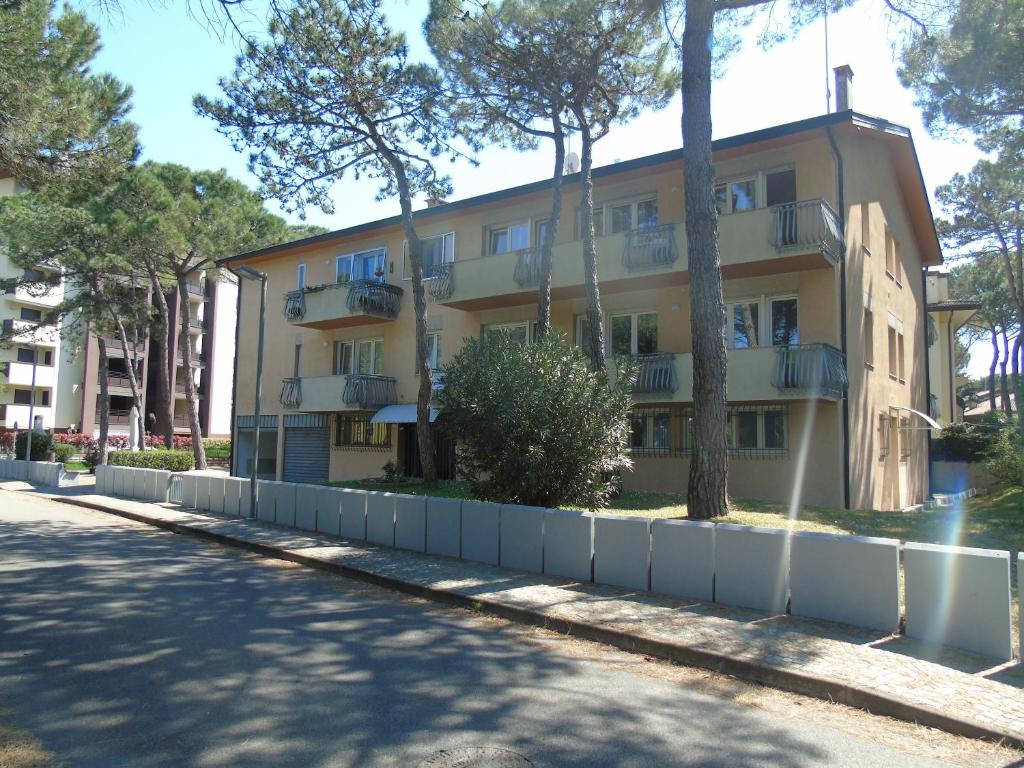 a yellow building with trees in front of a street at Villa Valeria in Lignano Sabbiadoro