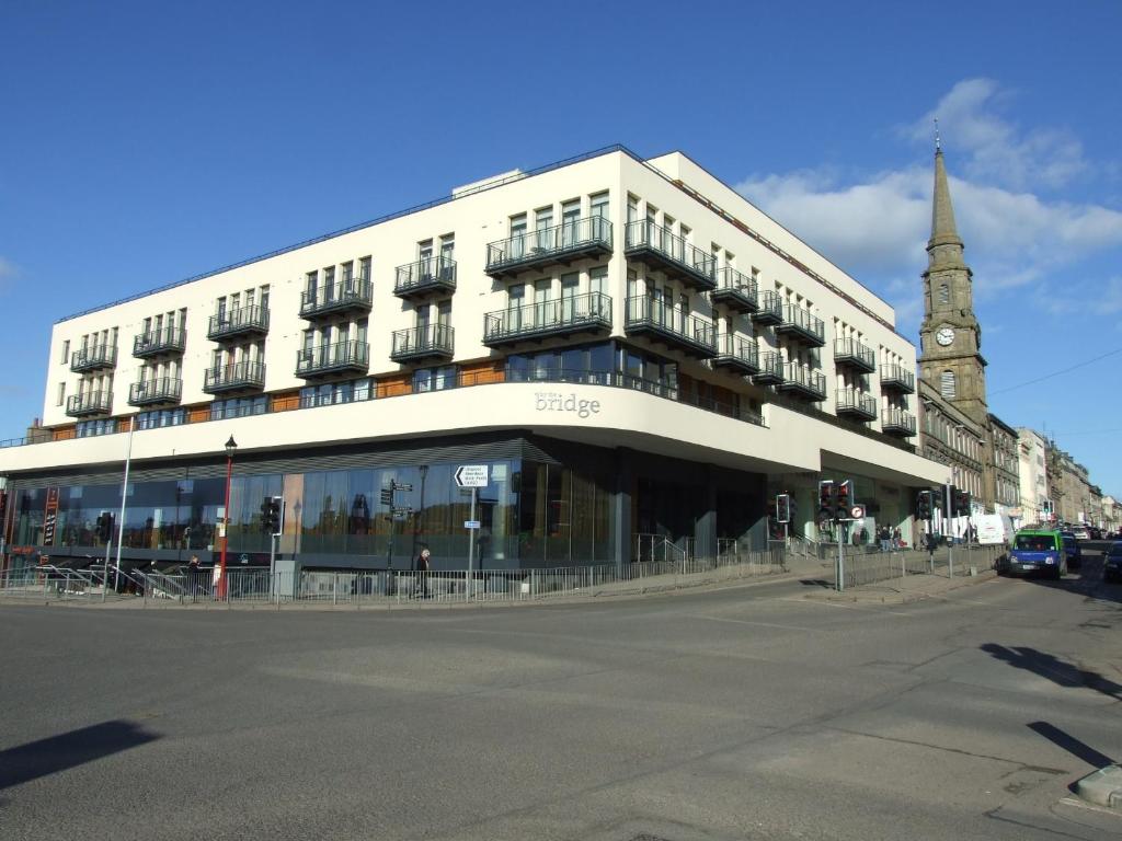 a large white building with a clock tower on a street at By The Bridge Apartments in Inverness