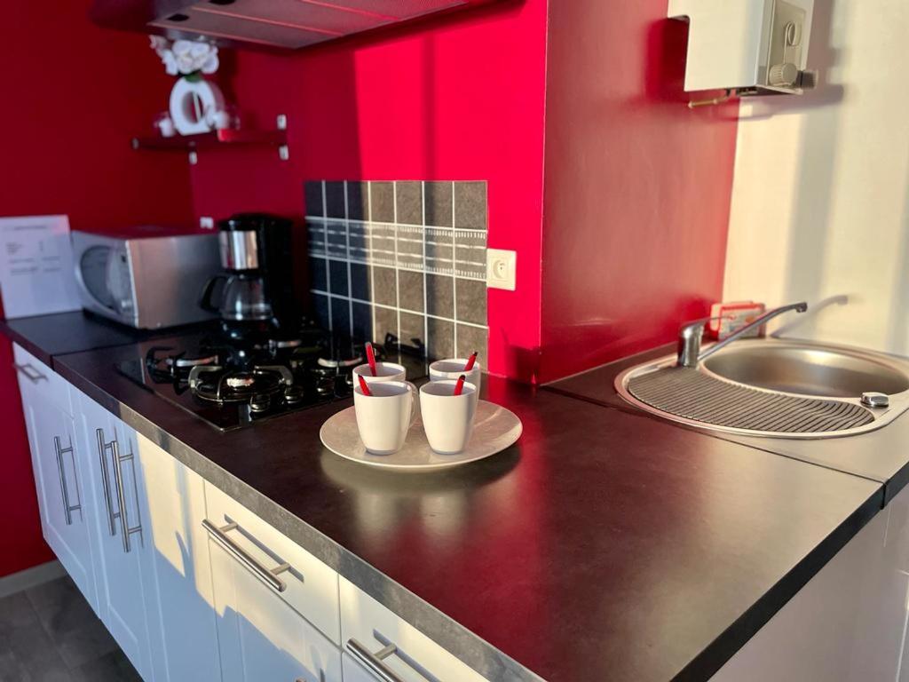 eine Küche mit roten Wänden und einer Theke mit Tassen in der Unterkunft BUBBLE GOM'Z in Saint-Hilaire-de-Riez