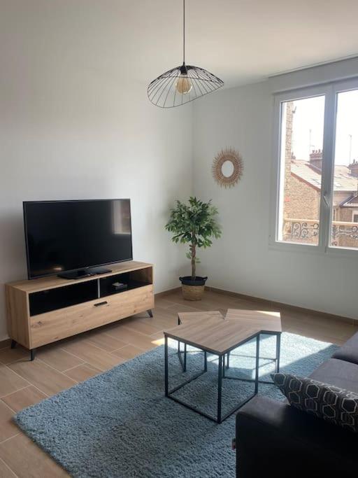 un salon avec une télévision à écran plat et une table dans l'établissement Le 202 de la gare: appartement neuf et climatisé, à Châlons-en-Champagne