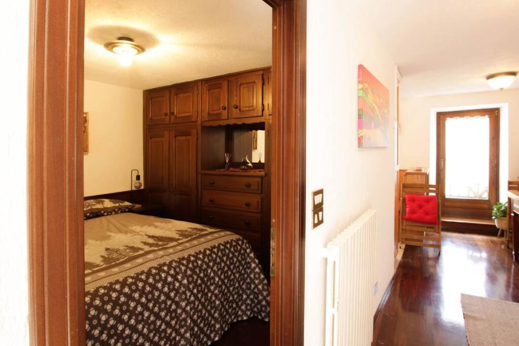 1 dormitorio con cama, armarios de madera y ventana en Maison Baradis - grazioso e tranquillo trilocale con vista montagne, en Allein