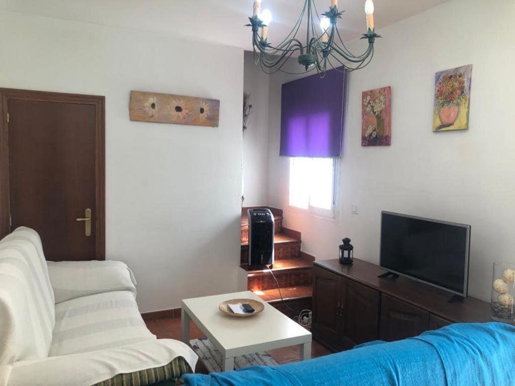 sala de estar con sofá y TV en Casa Cris, en Aracena