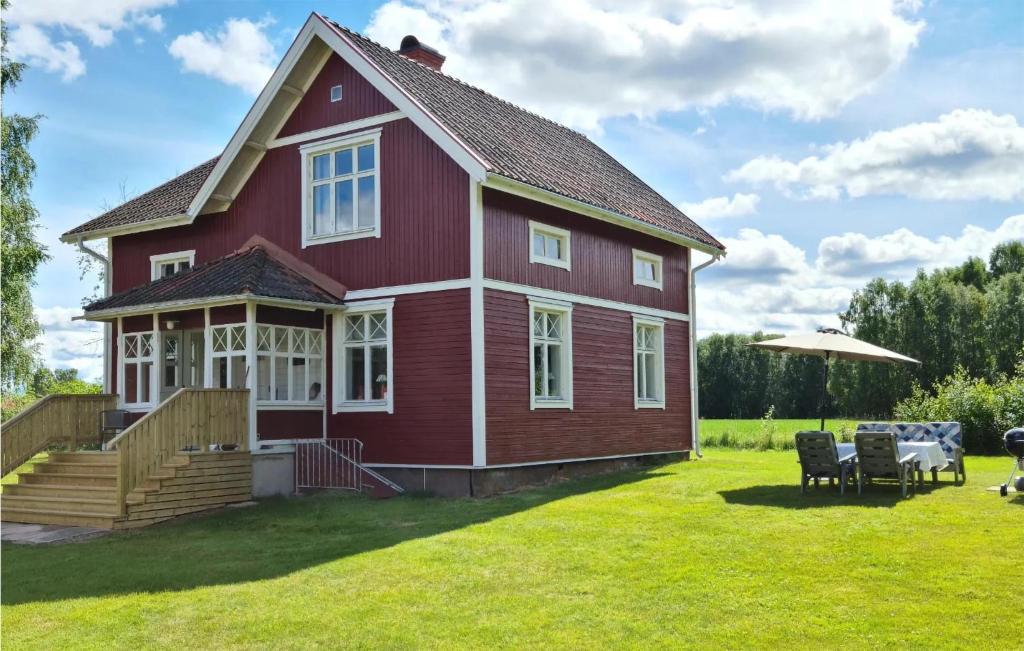 a red house with two chairs and an umbrella at Gorgeous Home In Venjan With House A Panoramic View in Västbygge