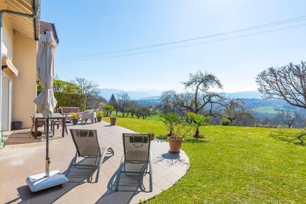 a patio with chairs and a table and an umbrella at Villa proche Annecy in Lovagny