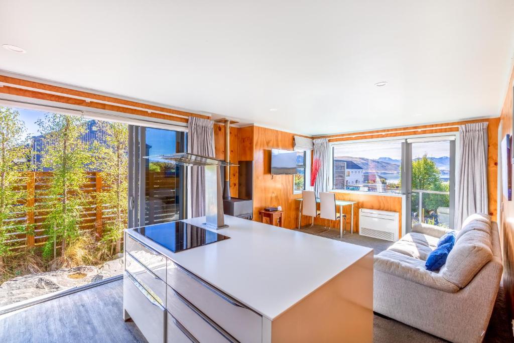 a kitchen with a white counter and a living room with windows at Tekapo Blue Cottage in Lake Tekapo