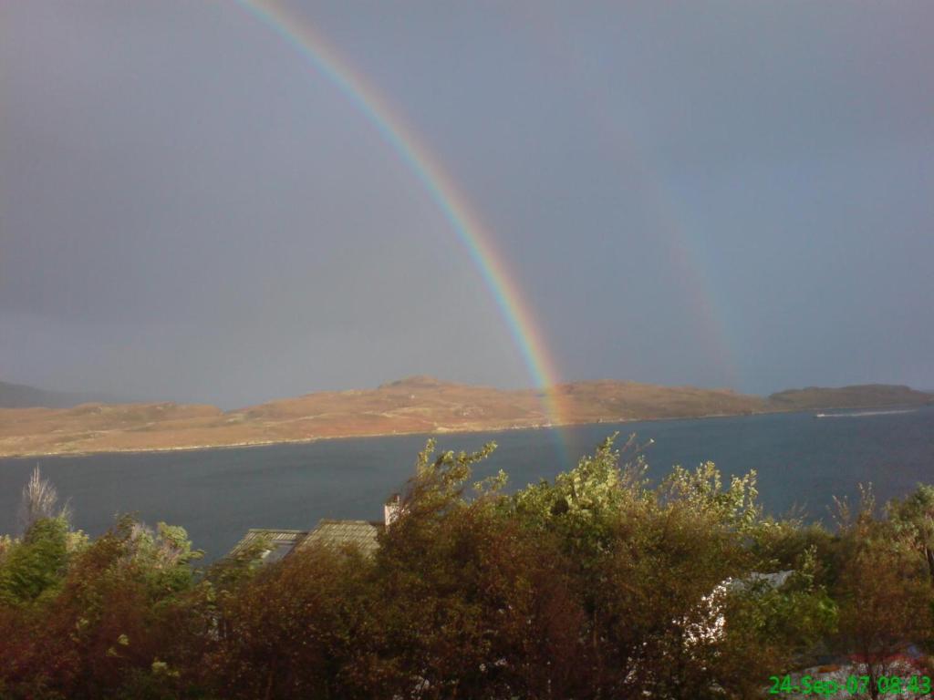 a rainbow in the sky over a body of water at Tigh na Fraoch in Flashader