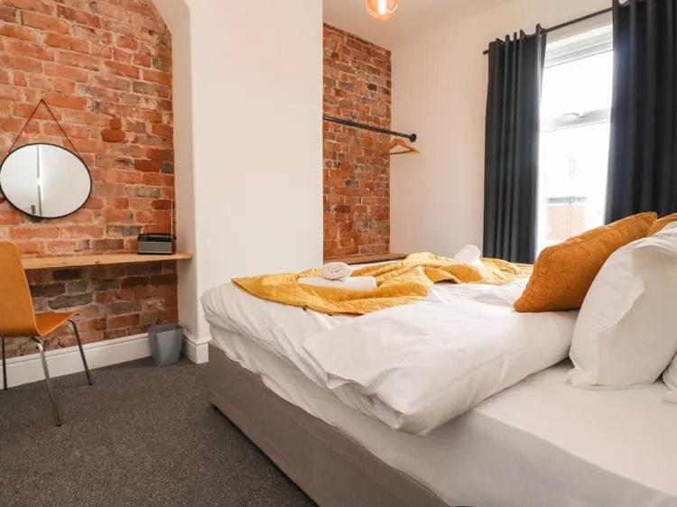 ein Schlafzimmer mit einem großen Bett mit Ziegelwand in der Unterkunft Magenta Melodies, 5 Bedroom House in Blackpool