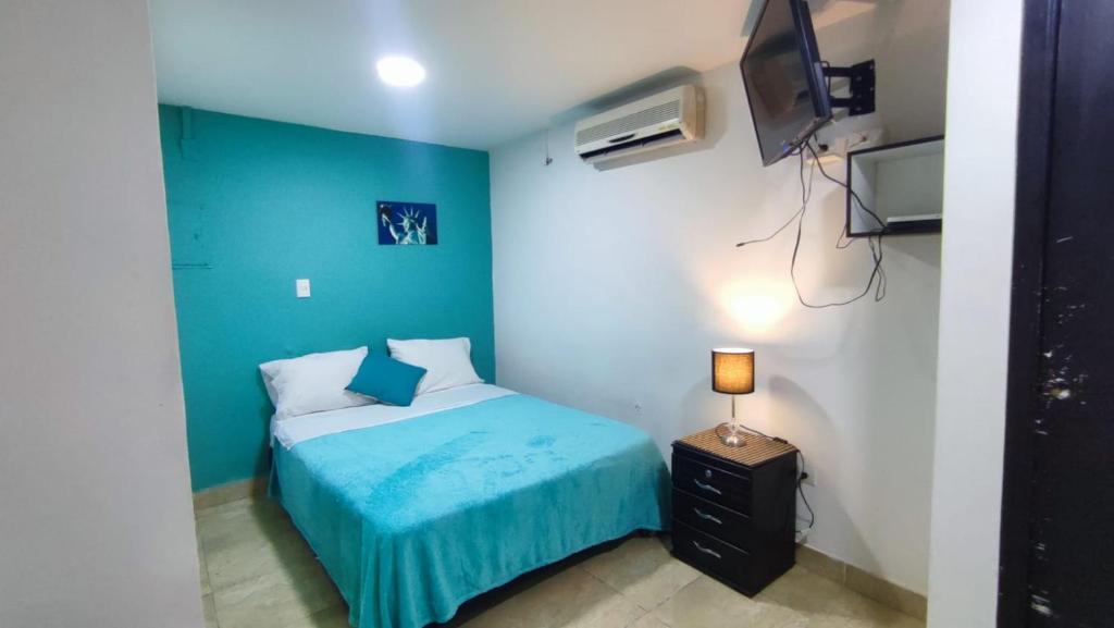 Dormitorio azul con cama y TV en Hotel Aqua lux, en Medellín