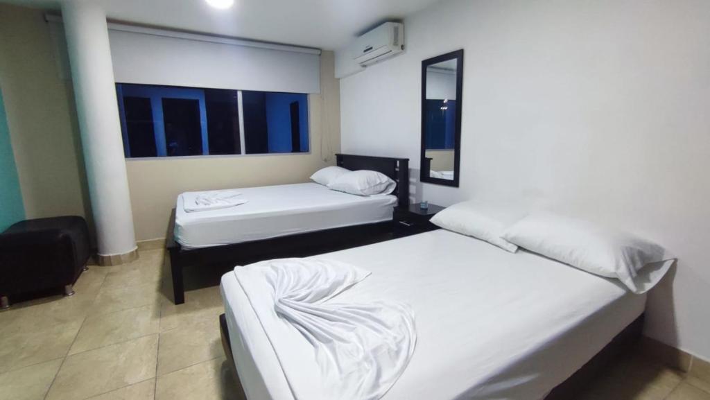 Habitación con 2 camas y 2 ventanas. en Hotel Aqua lux, en Medellín