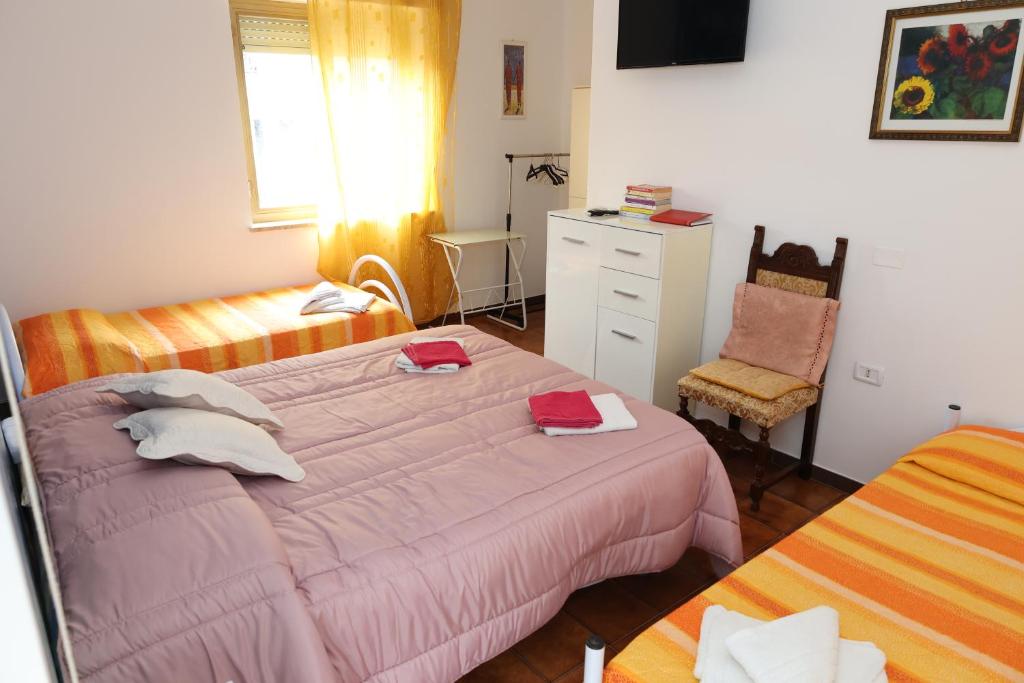 1 dormitorio con 2 camas y 1 silla en Le Gardenie b&b, en Marina di Schiavonea
