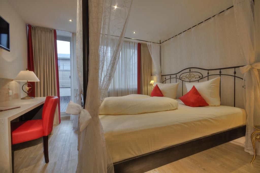 a bedroom with a bed and a red chair at Hotel Condor in Munich