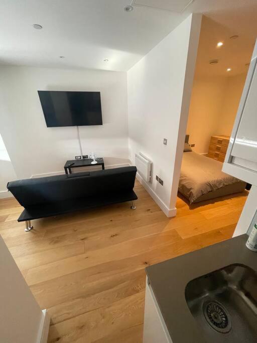 a living room with a black couch and a television at Vibrant flat in the city centre in Slough