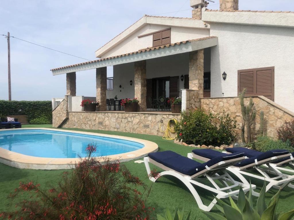 a house with a swimming pool and two lawn chairs at Mirariu in Els Muntells