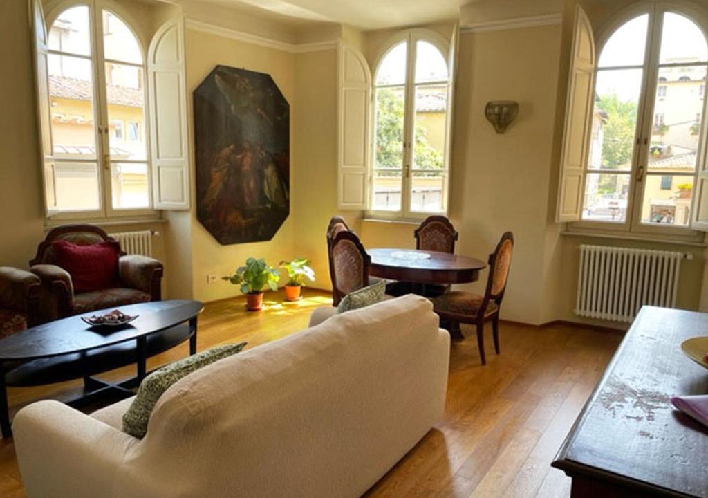 ein Wohnzimmer mit einem Sofa, einem Tisch und Stühlen in der Unterkunft Serena Apartment in Lucca
