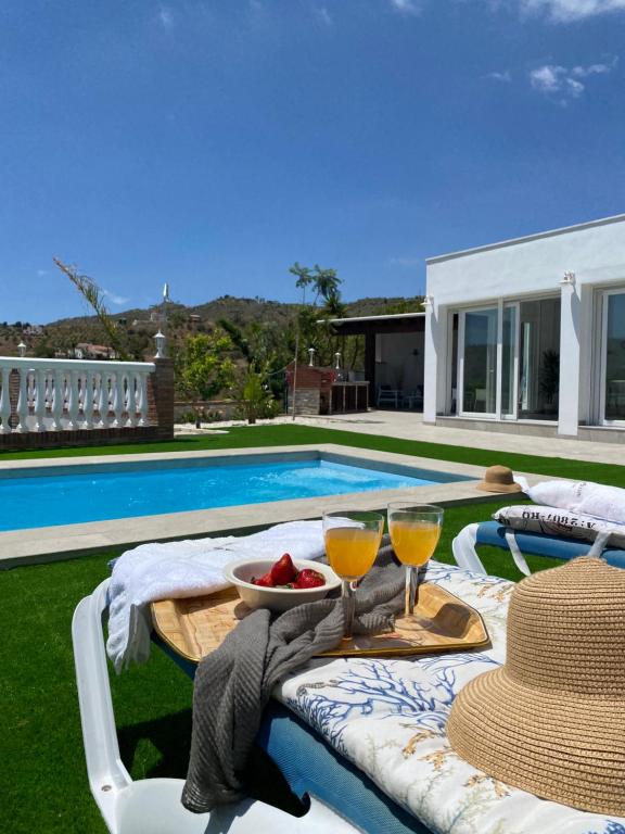 a table with two glasses of wine next to a swimming pool at Entre montañas in Árchez