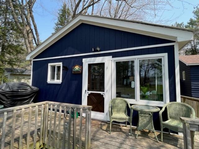 a blue tiny house with a table and chairs at The “Lily” waterfront Muskoka cottage in Utterson