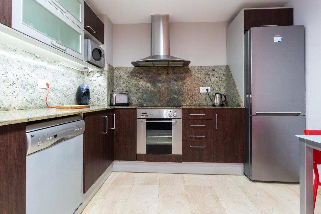 una cocina con armarios de madera y electrodomésticos de acero inoxidable en Apartament Granollers Up Live I, en Granollers