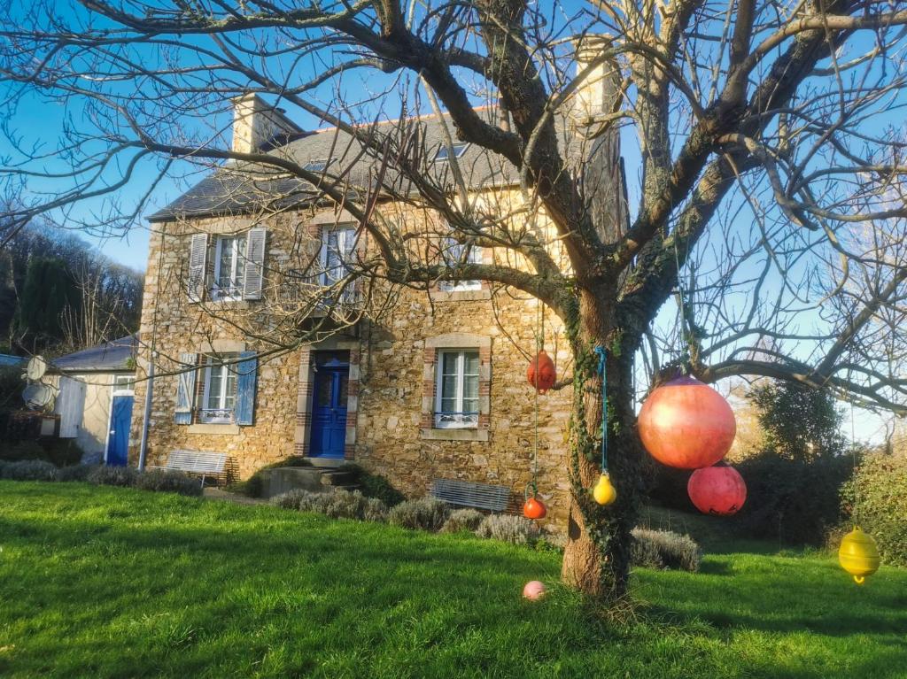une ancienne maison en pierre avec des ballons sur un arbre dans l'établissement Ker Yaël – Maison familiale avec grand jardin à 5min de la plage Saint Jean du doigt, à Saint-Jean-du-Doigt
