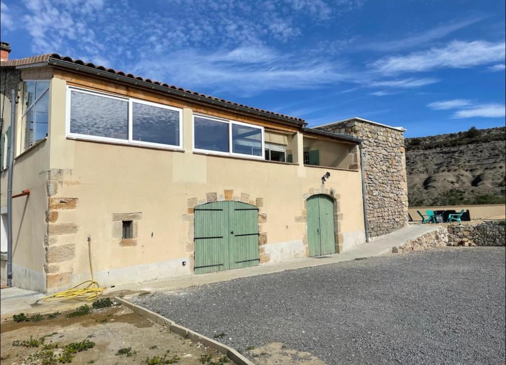 une maison avec des portes vertes et un mur en pierre dans l'établissement Mas de charme avec piscine chauffée, à Rosières