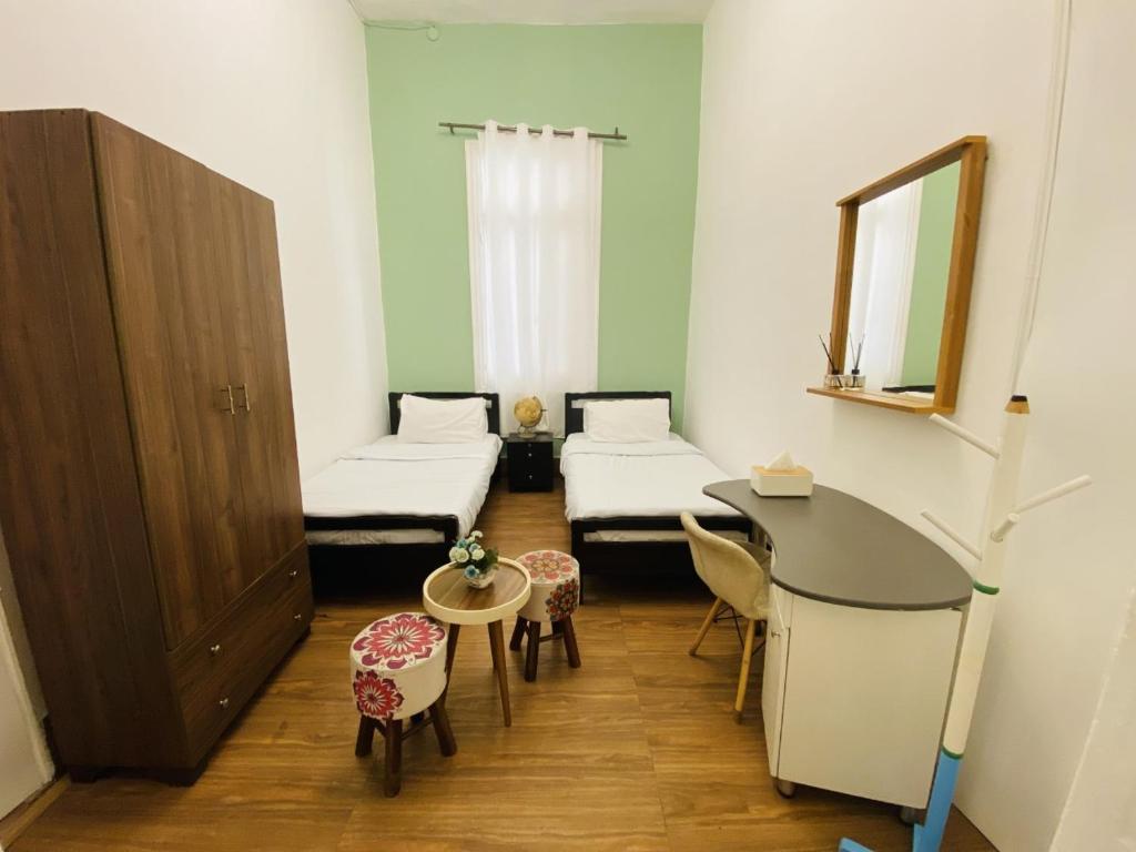 a room with two beds and a table and a mirror at City Hostel Dormitory in Trâblous