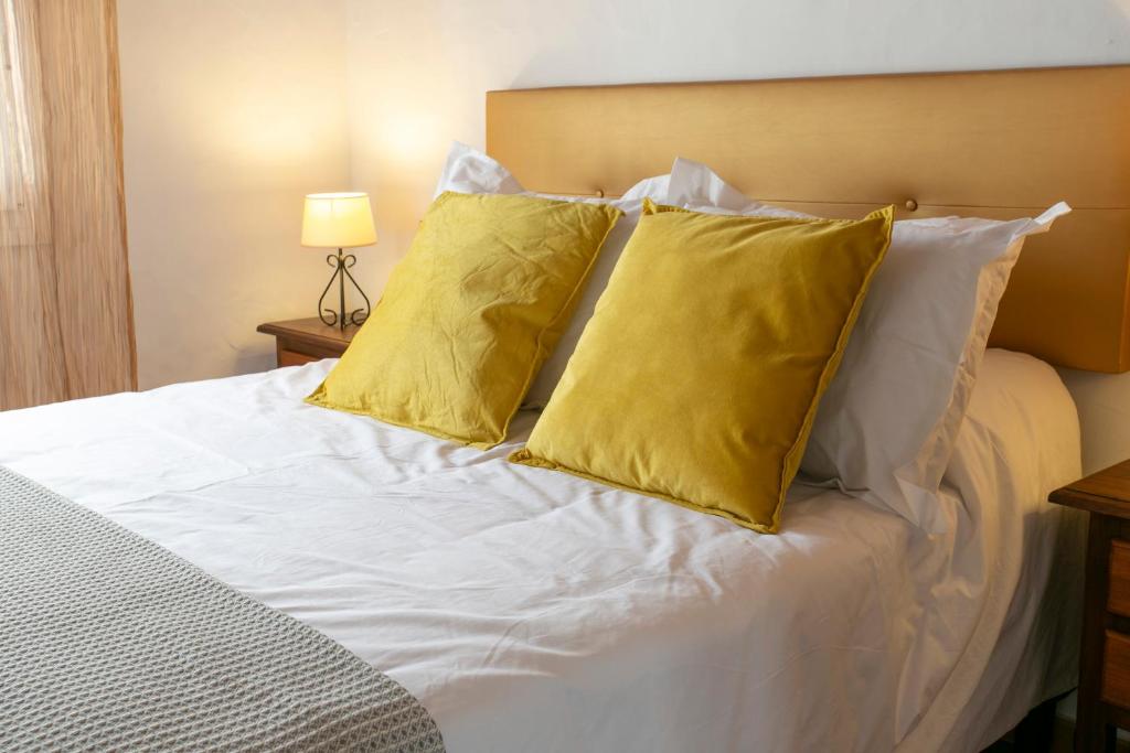 Una cama blanca con dos almohadas amarillas. en Estudio La Motilla, en Facinas