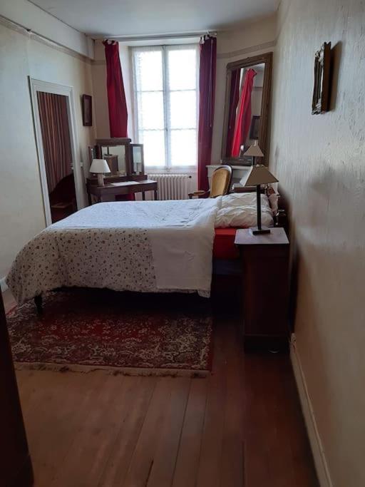 a bedroom with a bed and a desk and a window at La Volière in Champigny-sur-Veude