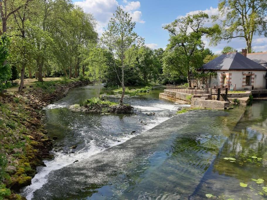 a river with a house in the background at La Volière in Champigny-sur-Veude