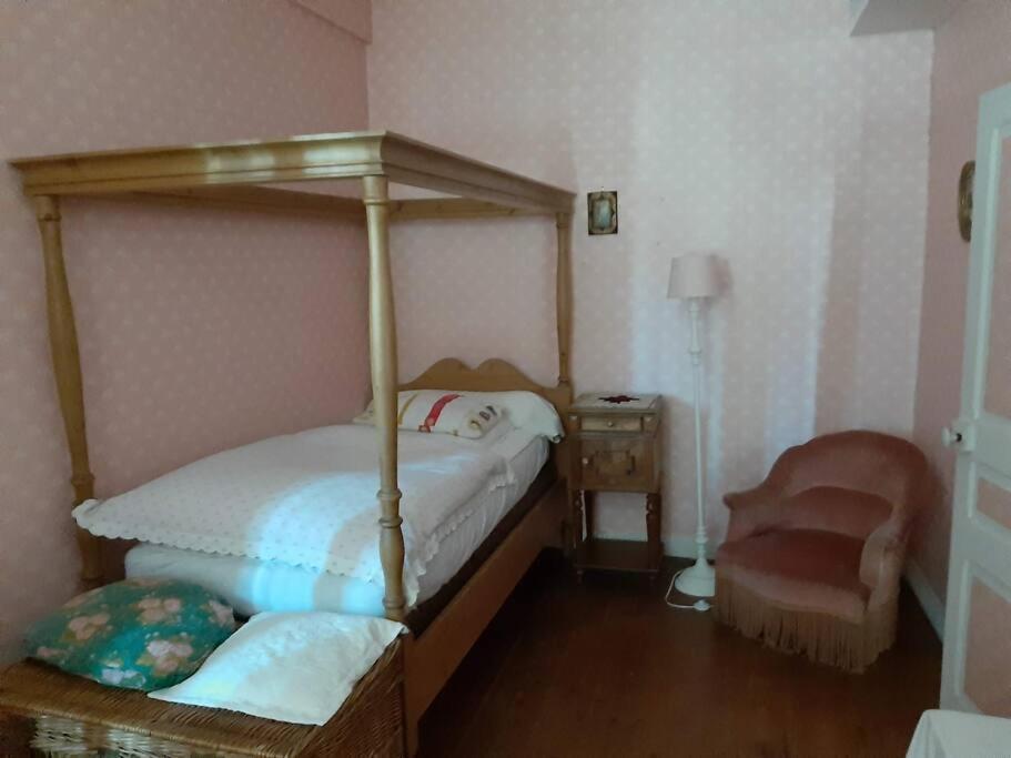 a bedroom with a canopy bed and a chair at La Volière in Champigny-sur-Veude