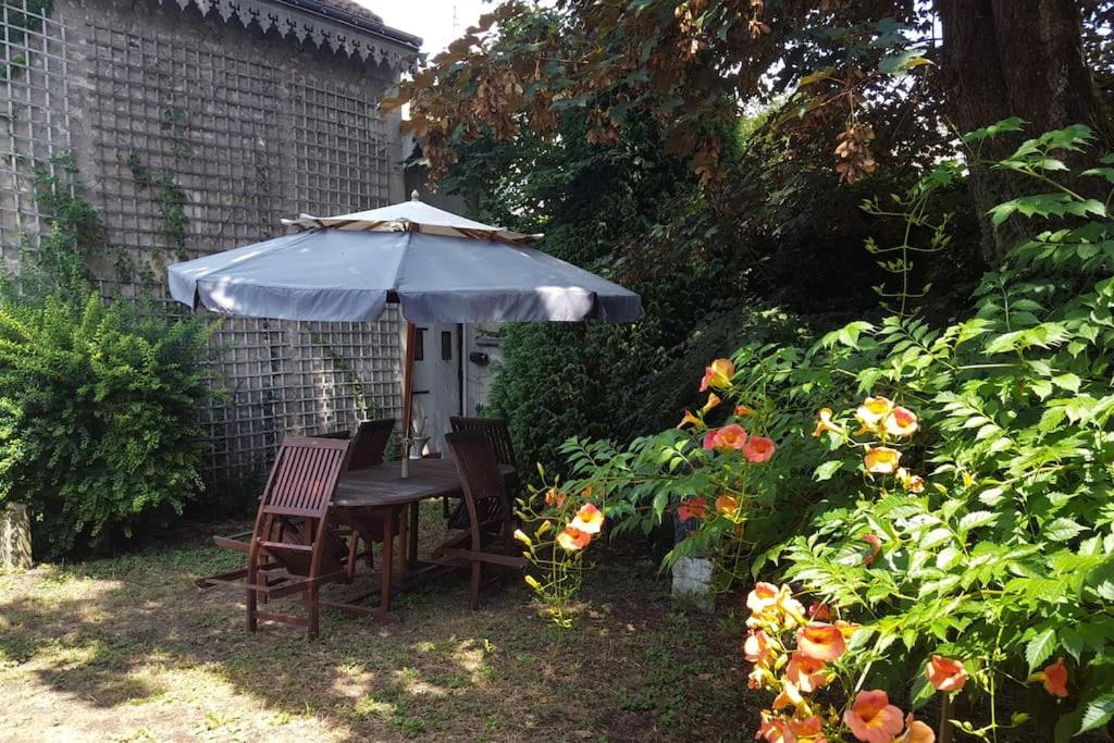 a table and chairs under an umbrella in a garden at La Volière in Champigny-sur-Veude