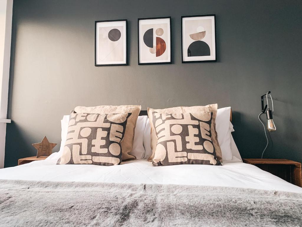 a bedroom with a white bed with three pictures on the wall at Grosvenor House by Solace Stays in Newport