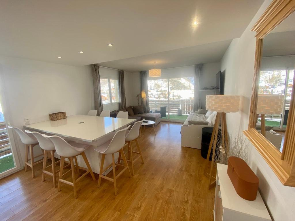 a dining room and living room with a table and chairs at 3 pièces la Foux d Allos vue montagne et station in La Foux