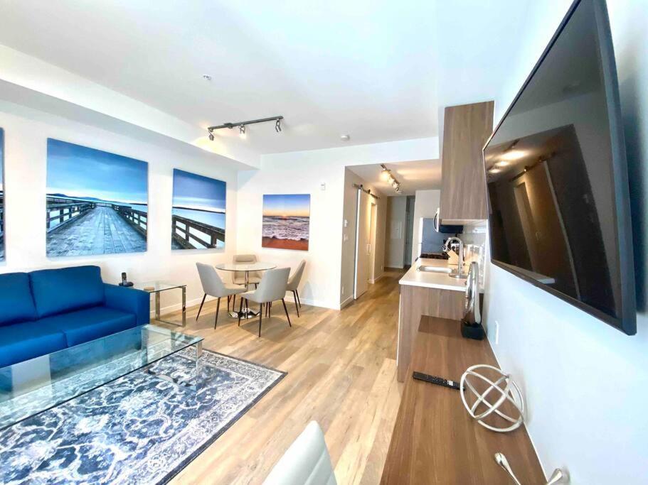 a living room with a blue couch and a tv at Perfect Brand New Condo Downtown Sidney in Sidney