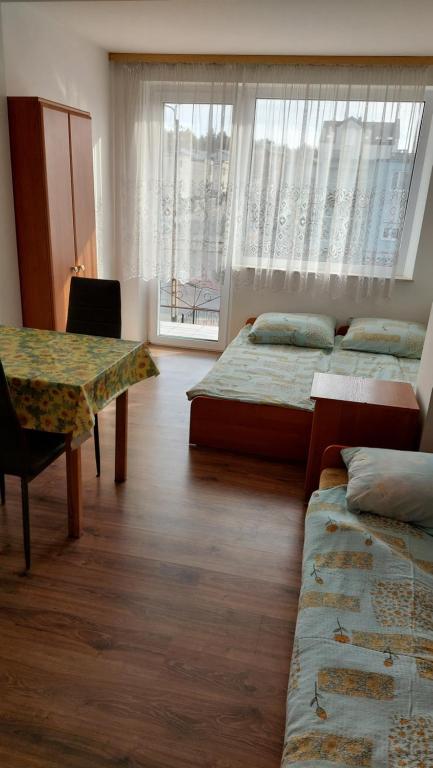 Habitación con 3 camas, mesa y ventana en Pokoje Gościnne Róża, en Władysławowo