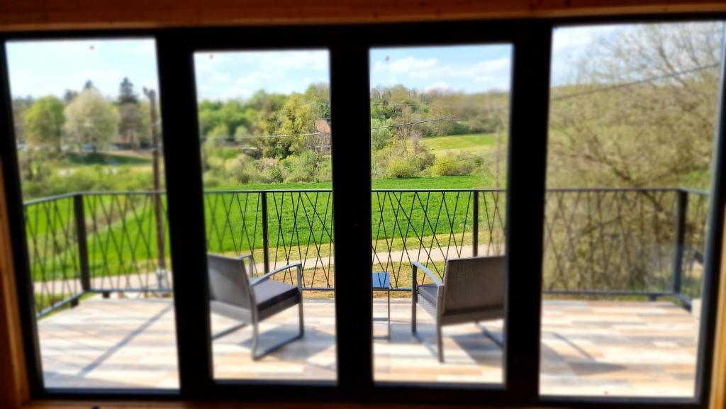 a view from a window of a balcony with two chairs at NEO resort jezero Bruje in Erdevik