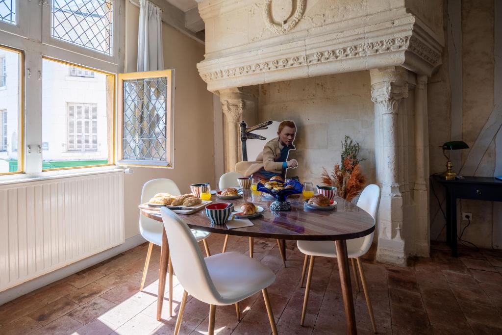 a man sitting at a dining room table with food on it at Mille Sabords 4 pers à 20 minutes de Beauval in Montrichard