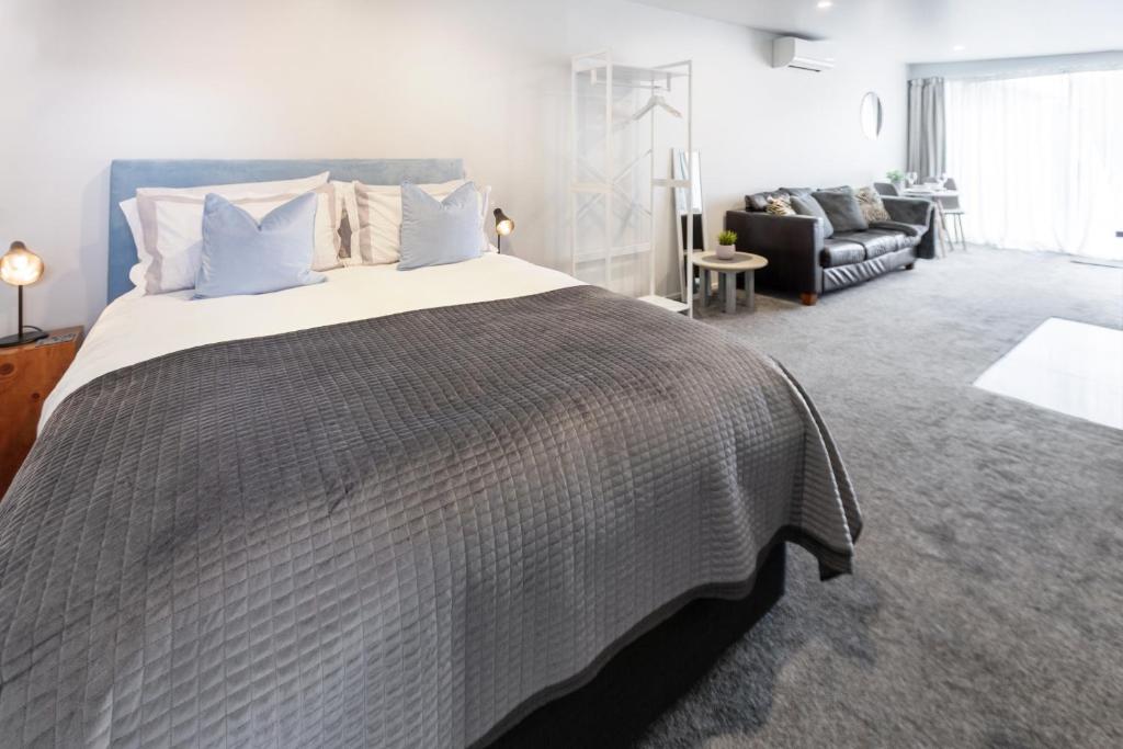 1 dormitorio con 1 cama grande y 1 sofá en St Albans Gem Single level studio with Queen bed en Christchurch
