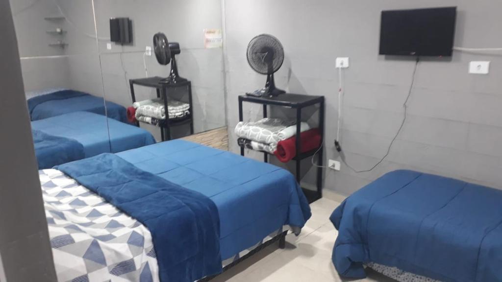 a room with two beds and a television in it at Pousada vithoria in Pinhais