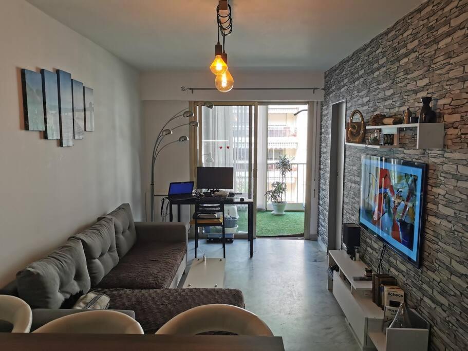 un salon avec un canapé et un mur de briques dans l'établissement Logement entier, appartement Antibes-Juan les Pins, à Antibes