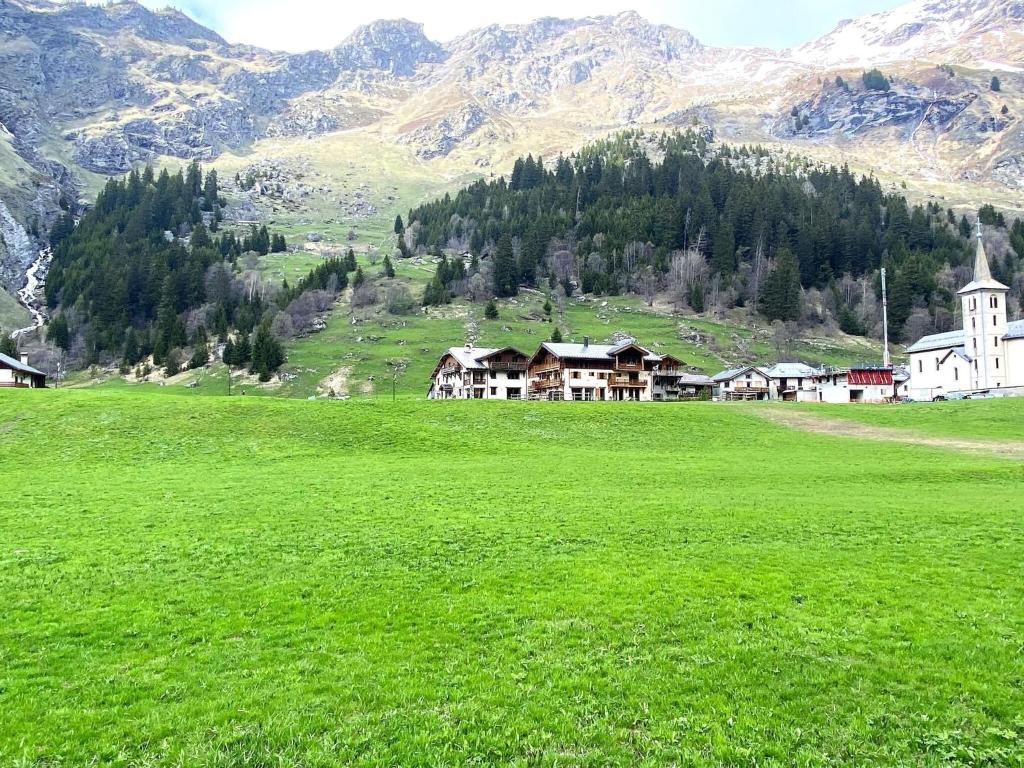 un champ d'herbe verte avec une église et une montagne dans l'établissement Alpine Chalet with Spa and pets, à Champagny-en-Vanoise