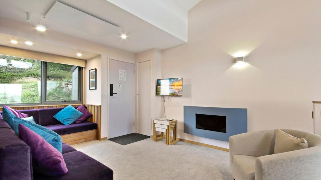 a living room with a couch and a fireplace at Snowtel 4 in Mount Hotham
