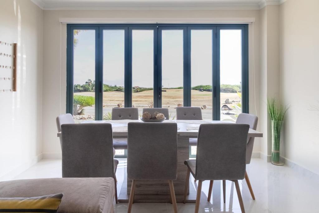 Un comedor con mesa y sillas y una gran ventana. en Spectacular apartment in tierra del sol golf course, en Palm-Eagle Beach