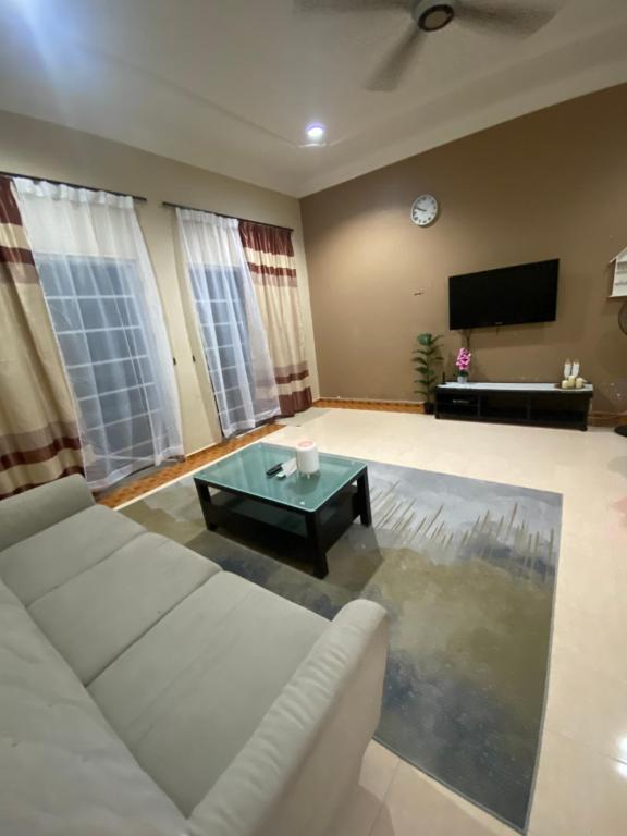 sala de estar con sofá blanco y mesa en The Esa Homestay Kemaman, en Cukai