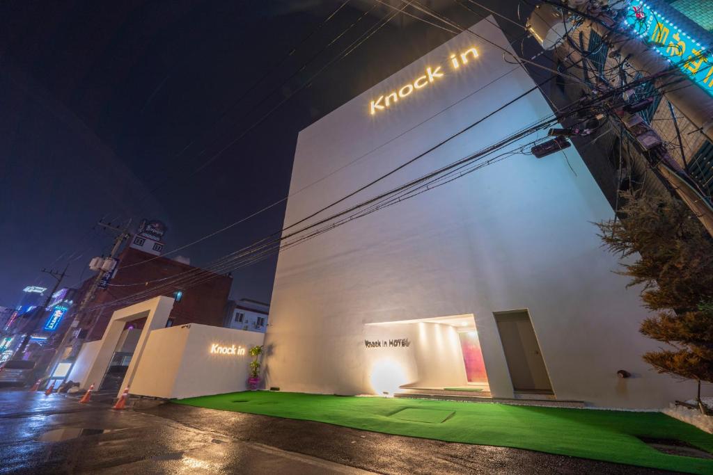 a building with a green lawn in front of it at night at Knock In Hotel Daejeon by ANNK in Daejeon