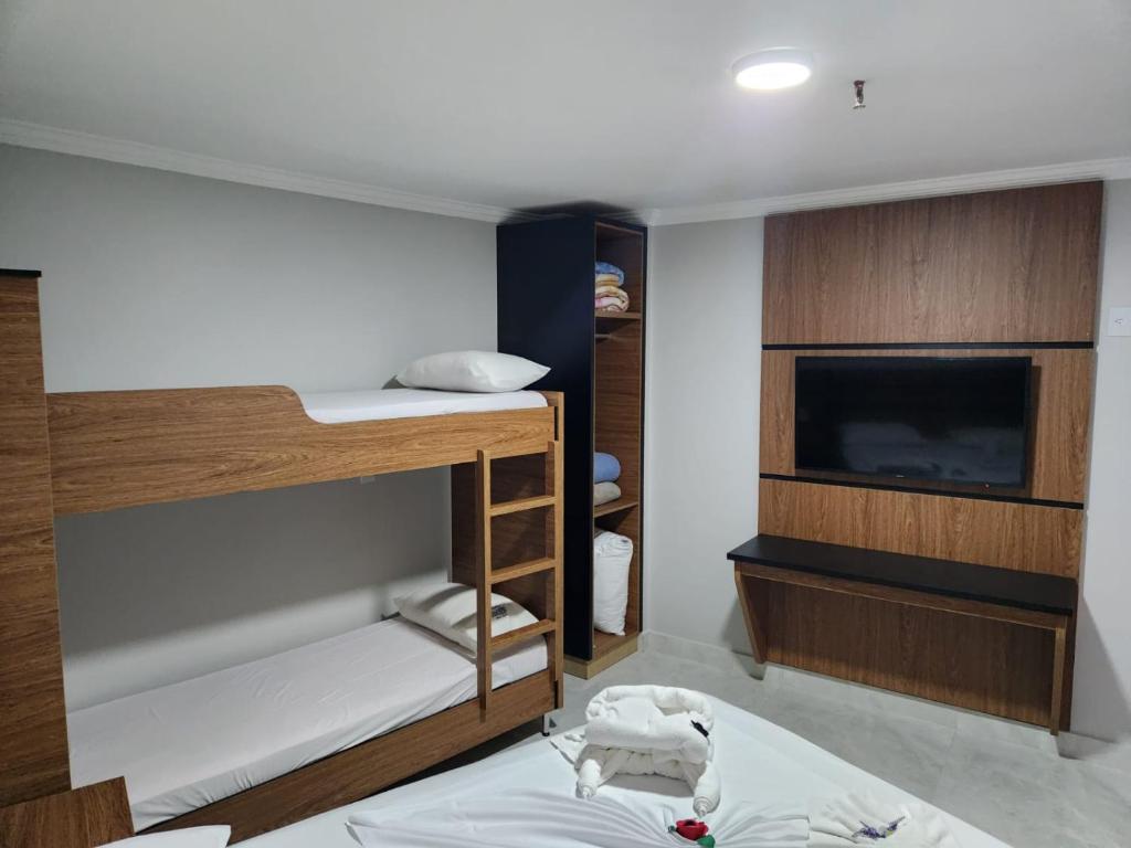 Cette chambre dispose de lits superposés et d'une télévision à écran plat. dans l'établissement Araras Apart Service Caldas Novas, à Caldas Novas