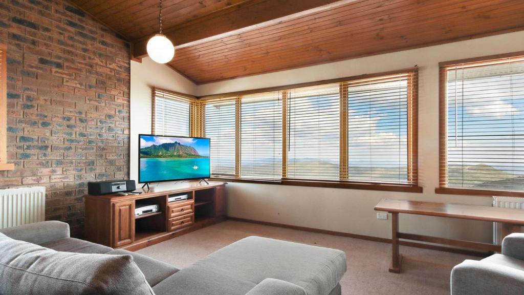 a living room with a couch and a tv and some windows at Lawlers 34 in Mount Hotham
