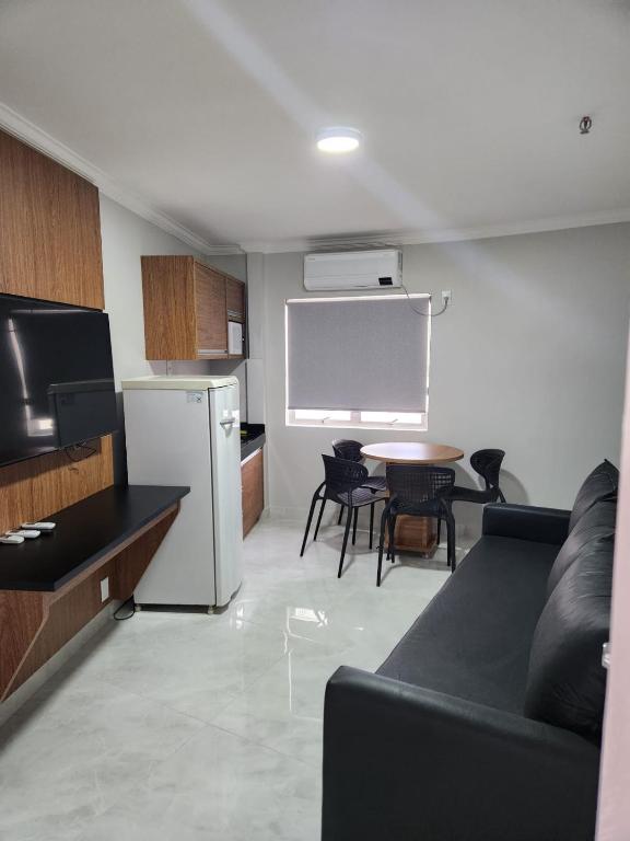 a living room with a couch and a kitchen with a table at WM Araras Apart Caldas Novas in Caldas Novas