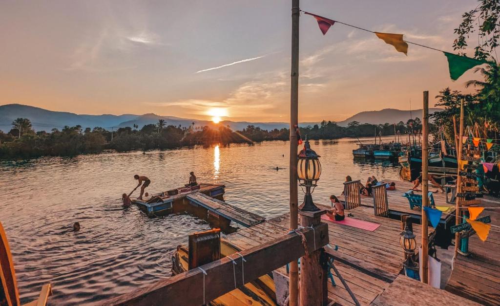 persone che saltano da un molo in acqua al tramonto di Yellow Sun Kampot a Kampot