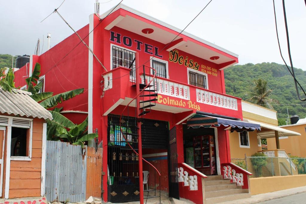 a red building with a hotel closest to the street at Aparta Hotel Los Deisy in Los Patos