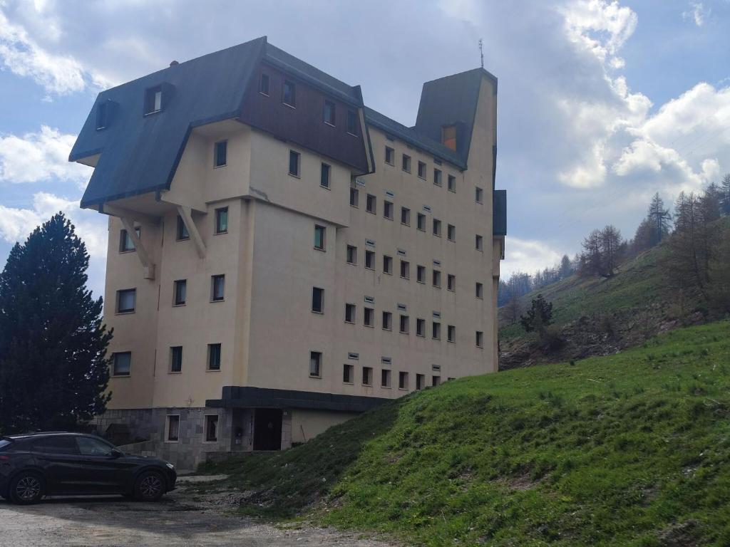 un bâtiment sur une colline avec une voiture garée devant dans l'établissement Alpine Escape with Charm, à Sestrières